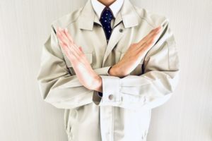 バツサインをする作業着姿の男性