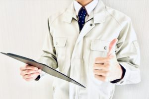 バインダーを持って親指を立てる作業着男性